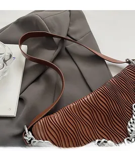 Detail of coffee pleated leather shoulder bag with stylish silver chain and strap