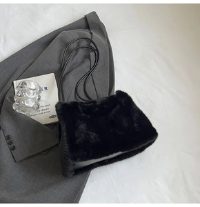Detailed texture of black faux fur shoulder bag placed on a grey blazer suit