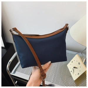 Detail of dark blue nylon shoulder bag with brown leather trim and metal zipper