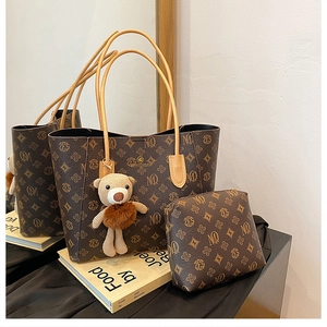 Brown monogram tote bag set with matching pouch and plush bear charm on a desk
