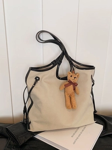 Minimalist beige canvas tote bag with black leather trim and cute brown teddy bear charm