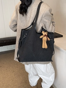 Large black canvas tote bag with leather handles and a cute bear charm for daily wear