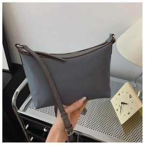 Detail of blue-grey nylon crossbody bag with brown trim and woven texture strap