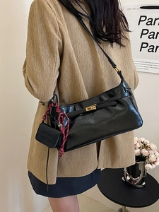 Retro black leather hobo bag with gold twist lock and woven strap accent on a shoulder