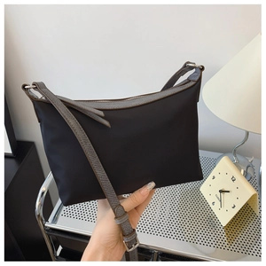 Detail of minimalist black nylon shoulder bag with silver zipper and snake-pattern strap