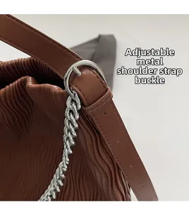 Close-up of adjustable strap buckle and silver chain on textured brown tote bag