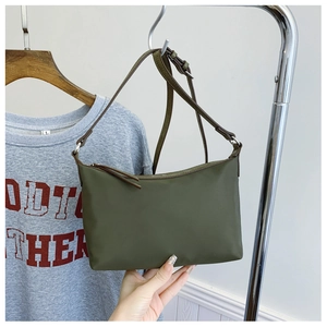 Close-up of olive green nylon shoulder bag with adjustable strap and sleek zipper closure