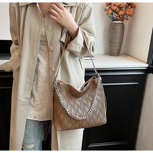 Macro shot of brown pleated texture and silver chain detail on the stylish bucket bag