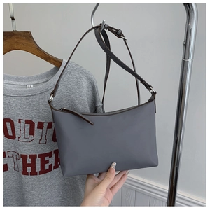 Detail of gray nylon shoulder bag with brown leather trim and silver zipper hardware