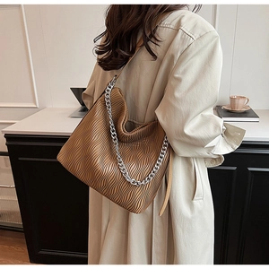 Detailed view of brown tote bag with vertical pleats and decorative silver chain strap