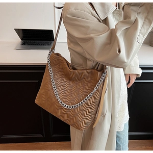 Detail of a brown pleated PU leather bucket bag with silver chain and shoulder strap