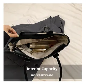 Macro view of the large internal capacity and multi-functional pockets of this black tote bag