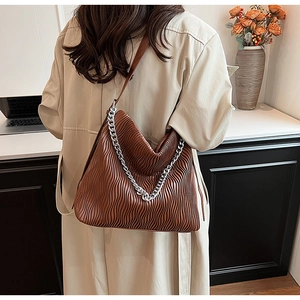 Detail of brown pleated bucket bag with silver chain strap and leather handle