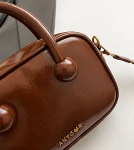 Nahaufnahme der dunkelbraunen Handtasche aus poliertem Leder mit NTOUR-Metalllogo