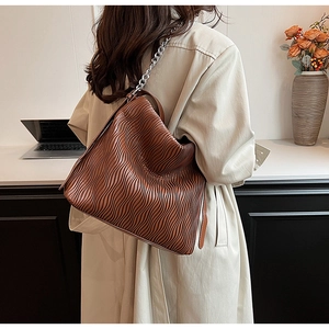 Detail of dark brown pleated texture shoulder bag with stylish silver chain strap