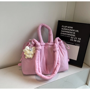Detalle de bolso acolchado rosa con cordones laterales y un colgante de peluche suave