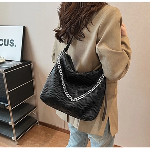 Detail of black pleated bucket bag with silver chain handle and soft PU leather texture