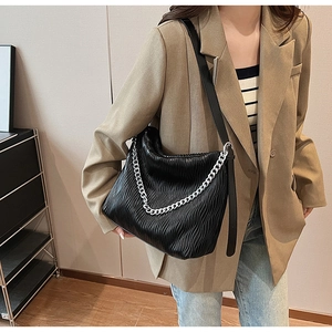 Detailed view of black pleated PU leather bucket bag with a silver chain ornament