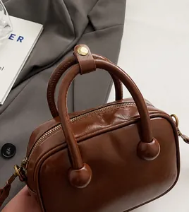 Detailansicht der dunkelbraunen Retro-Handtasche mit Metallreißverschluss und Goldbeschlägen