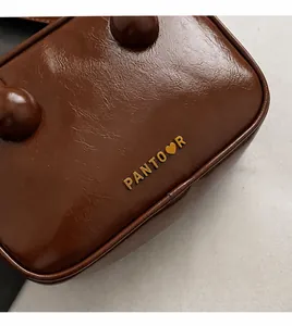 Detailansicht der braunen Ledertasche mit goldenem Pantoor-Logo und Herz-Detail im Leder