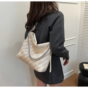 Detail of pleated cream tote bag with silver chain strap and crossbody shoulder strap