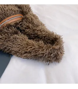 Detailed macro shot of the deep brown faux fur texture and leather-edged metal zipper