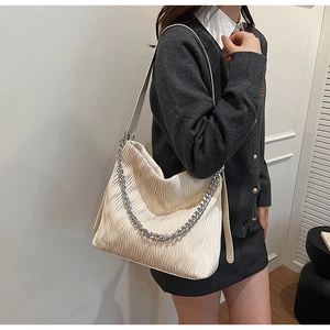 Detail of off-white pleated shoulder bag featuring a chunky silver chain and soft texture