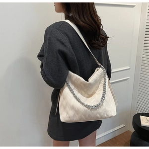 Detail of cream pleated bucket bag with silver chain strap and wavy faux leather texture