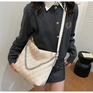 Detail of cream pleated shoulder bag with silver chain and textured PU leather finish
