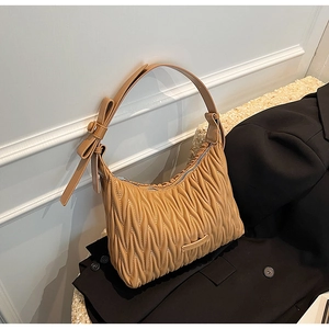 Close-up of the matelassé pleated texture and leather bow detail on the camel shoulder bag