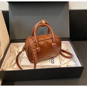 Nahaufnahme der dunkelbraunen Lederhandtasche mit Goldlogo in einer Geschenkbox
