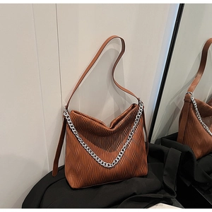 Macro detail of caramel brown pleated leather bag with silver chain and adjustable strap