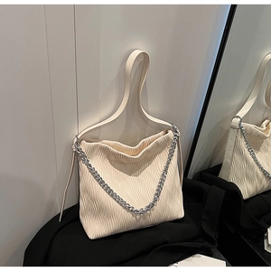 Close-up of pleated texture and silver chain detail on cream bucket shoulder bag