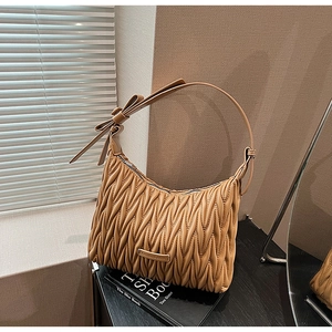 Detailed view of caramel pleated leather bag with metal logo and large bow strap