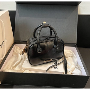Detailaufnahme der glänzenden schwarzen Handtasche mit goldenem PANTDOR Logo im Set