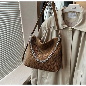 Detail of pleated brown leather bucket bag with silver metal chain on white hanger