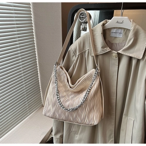 Detail of cream pleated shoulder bag with stylish silver chain and accordion texture