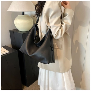Detail of black pebbled leather tote bag with gold zipper and adjustable buckle strap