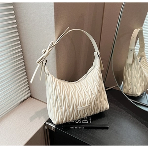 Close-up of the pleated matelassé texture and bow detail on this beige hobo shoulder bag