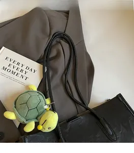 Dettaglio borsa tote in pelle nera testurizzata con un grazioso ciondolo a forma di tartaruga