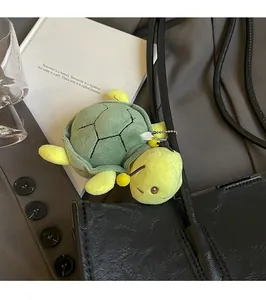 Dettaglio del ciondolo a tartaruga in peluche verde e giallo su borsa in pelle nera