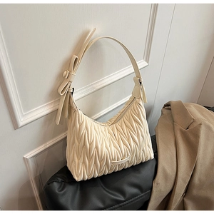 Macro detail of cream pleated matelassé shoulder bag with bow and silver logo plate