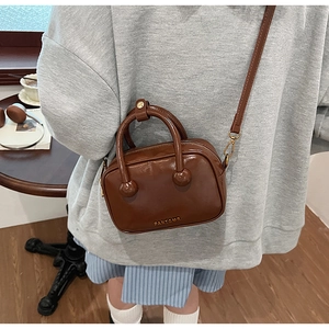 Detailansicht der braunen Vintage-Leder-Umhängetasche mit Goldlogo und Zylindergriff