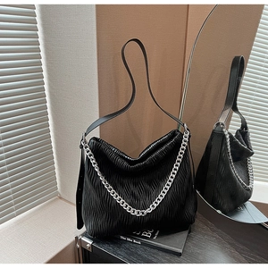 Detail of the black pleated leather bucket bag with a bold silver chain and texture