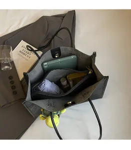 Dettaglio dell'interno capiente di questa borsa tote nera con oggetti di uso quotidiano