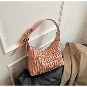 Close-up of pleated mauve underarm bag with decorative bow and metallic logo detail