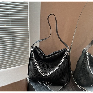 Close-up of black pleated tote bag with silver chain detail and premium leather texture