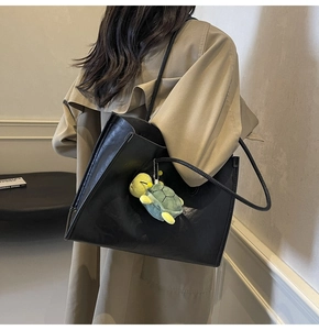 Dettaglio borsa tote in pelle nera con un simpatico ciondolo a tartaruga sulla tracolla