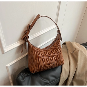 Detailed view of brown matelassé pleated leather shoulder bag with decorative bow