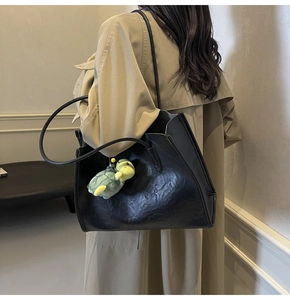 Dettaglio borsa tote nera in pelle stropicciata con decorazione a forma di tartaruga verde